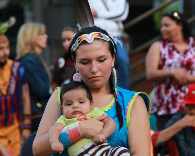 Native mother and child sitting together at a community event.